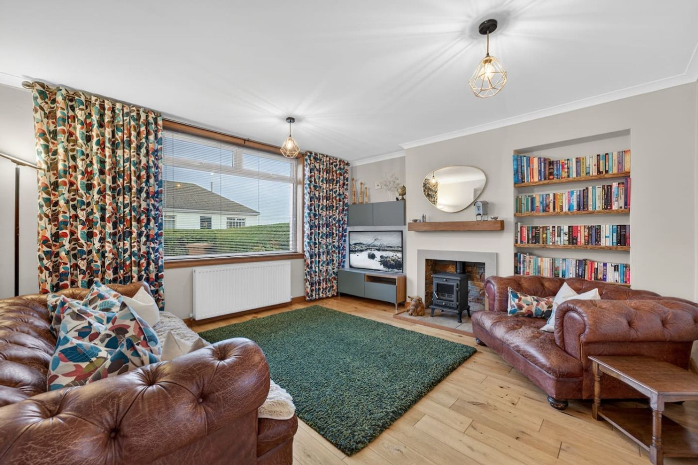 The Bruadair living room: leather sofas, wood stove, and a book wall.