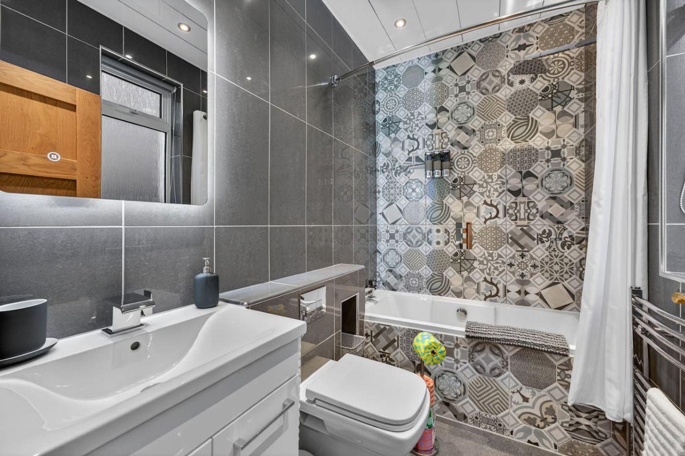 The bathroom: vanity, bath, and patterned tiles.